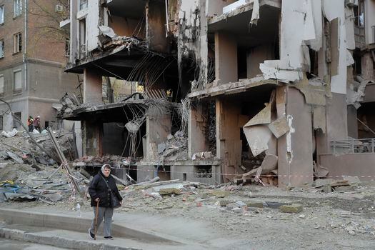 Una mujer camina por una calle de Kiev que fue bombardeada por Rusia; el ataque dejó evidentes daños en edificios residenciales. 
