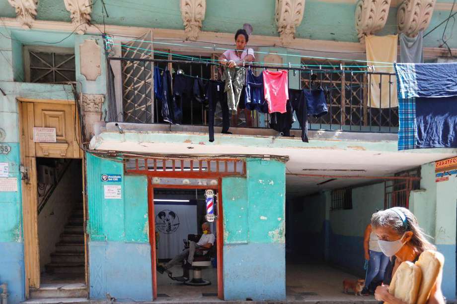Una mujer protegida con tapabocas camina frente a una vivienda en La Habana (Cuba), en donde se registra una segunda ola de coronavirus.
