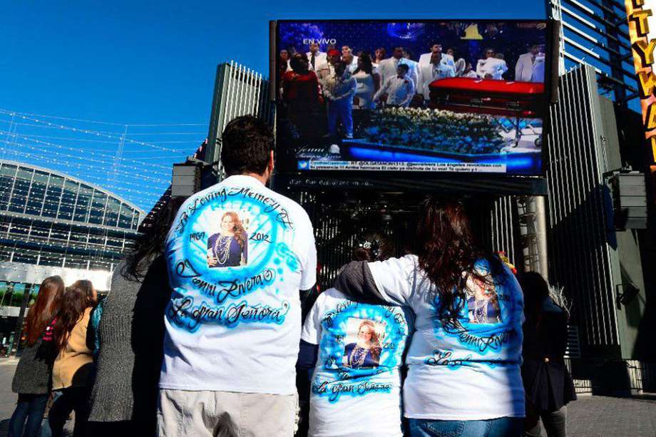 Seguidores de la fallecida cantante Jenni Rivera siguen la "ceremonia de graduación al cielo" de la "Diva de la banda" a través de una pantalla gigante puesta en la puerta del Gibson Amphitheatre de Los Ángeles en California (EEUU). / AFP