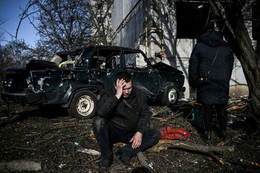 Un hombre se sienta afuera de su edificio destruido después de los bombardeos rusos en la ciudad de Chuguiv, en el este de Ucrania.