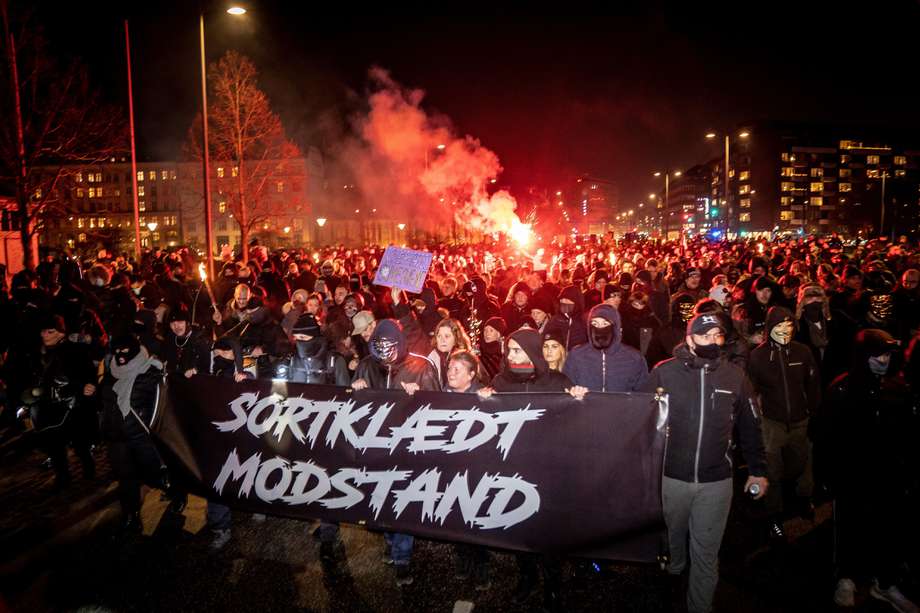 Los manifestantes marchan con una pancarta que dice 'Resistencia vestida de negro' durante una marcha de protesta organizada por el grupo radical 'Hombres de Dinamarca Negra' contra las restricciones introducidas por el gobierno danés durante la pandemia del nuevo coronavirus (Covid-19), en Copenhague el 23 de enero. 2021.