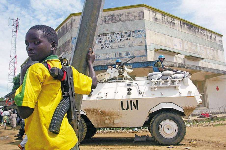 FILE In this May 30, 2003 file photo, a child fighter of the rebel Union of Congolese Patriots, then in control the Congolese town of Bunia, stands near a United Nations armored personnel carrier near the UN compound in Bunia, Congo. Judges at a war crimes tribunal Wednesday, March 14, 2012, convicted Congolese warlord Thomas Lubanga of snatching children from the street and turning them into killers, in the International Criminal Court's landmark first judgment 10 years after it was established. Prosecutors said Lubanga led the Union of Congolese Patriots political group and commanded its armed wing, the Patriotic Forces for the Liberation of Congo, which recruited children 'sometimes by force, other times voluntarily' into its ranks to fight in a brutal ethnic conflict in the Ituri region of eastern Congo.(AP Photo/Karel Prinsloo)