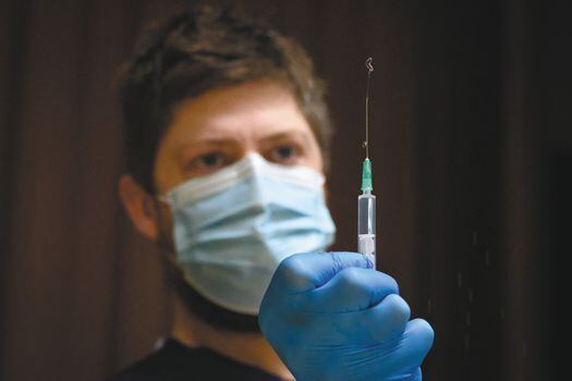 Un paramédico con una jeringa prepara una inyección de la vacuna Pfizer-BioNTech. 
