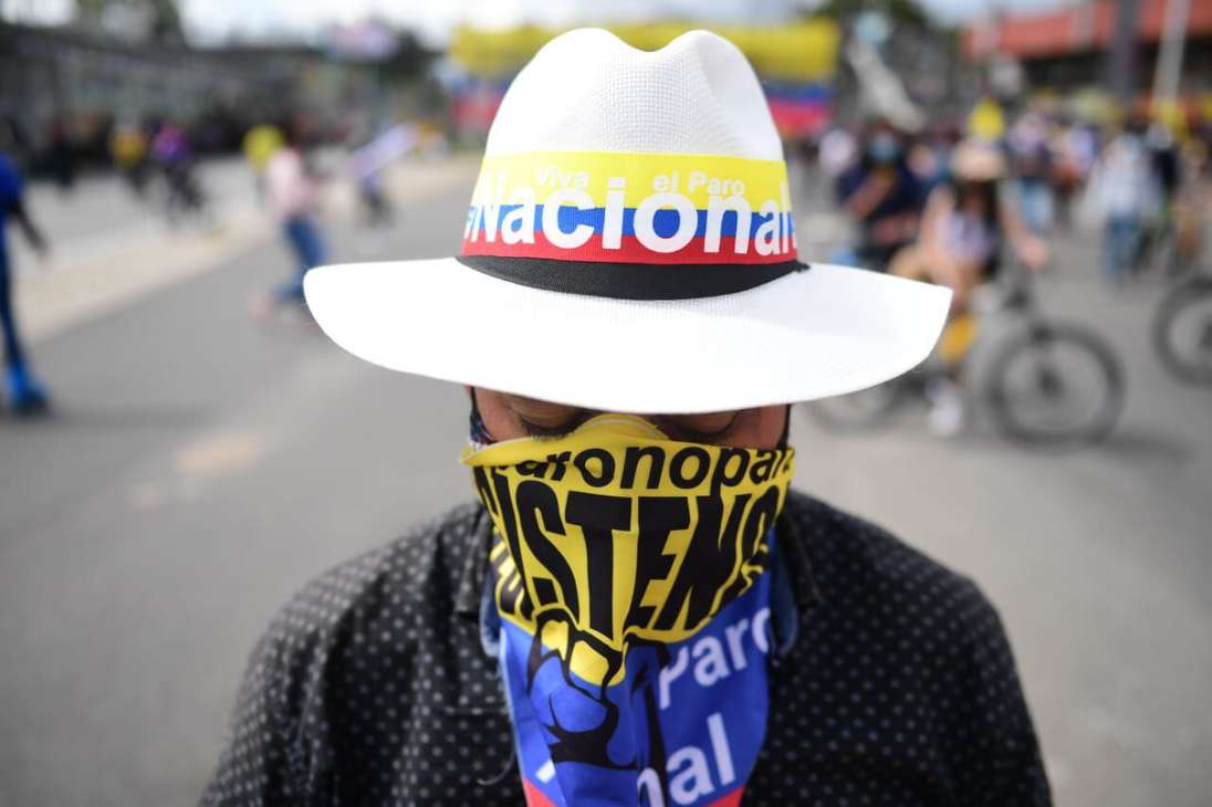 Un hombre con sombrero blanco y una pañoleta con mensajes y los colores de la bandera de Colombia
