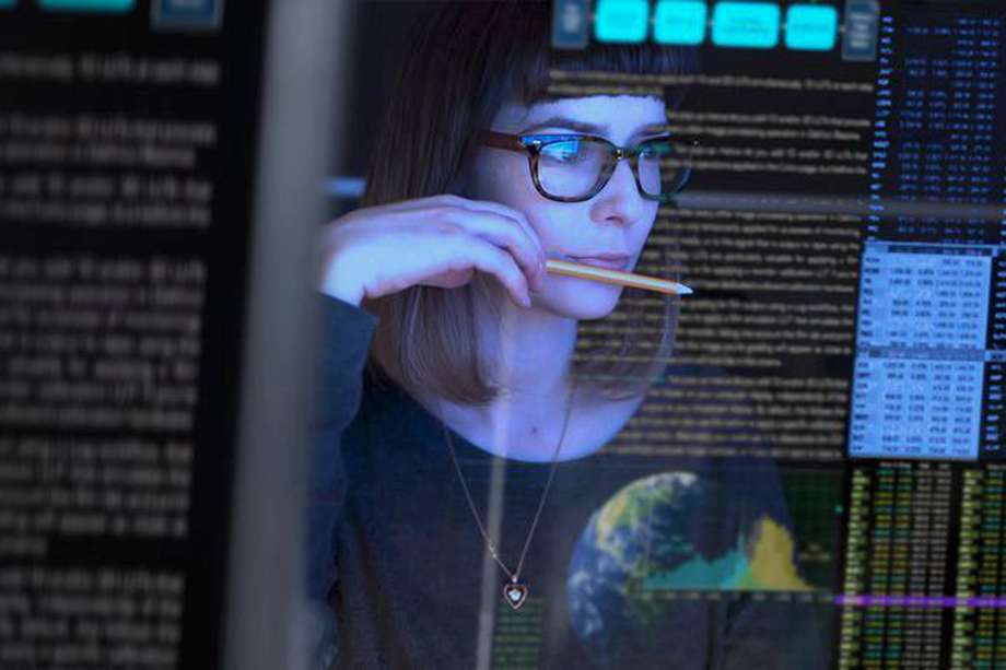 Stock image of a beautiful young woman studying a see through computer screen & contemplating.