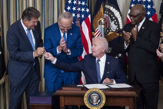 El presidente Joe Biden entrega el bolígrafo con el que firmó la Ley de Reducción de la Inflación al Senador demócrata Joe Manchin. 