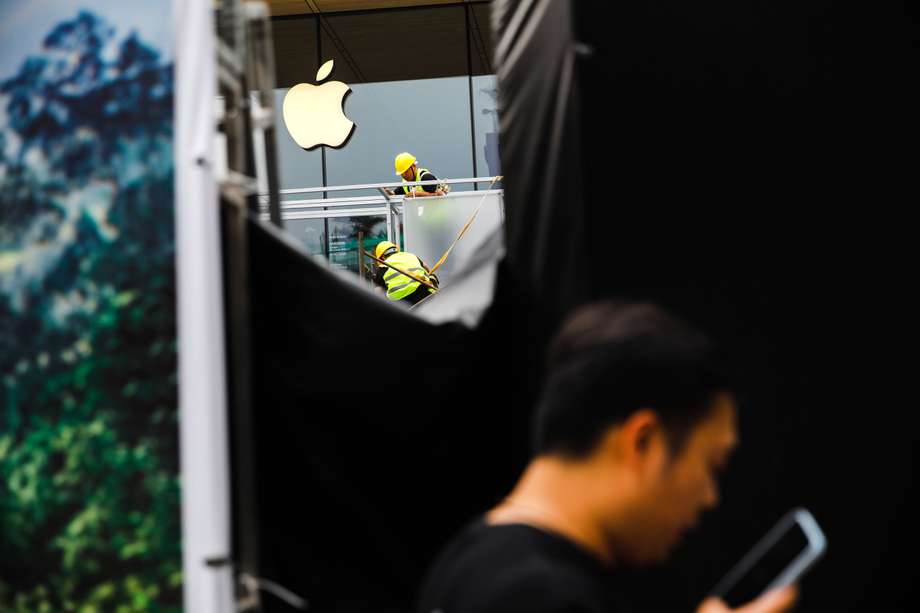 Imagen de referencia de un trabajador en Beijing consultando su teléfono con un logo de Apple al fondo. El impuesto global a multinacionales, como Apple, no ha cumplido el propósito inicial por unos malos diseño y aplicación del instrumento. EFE/EPA/WU HAO

