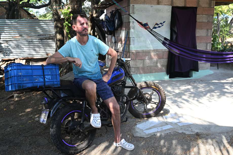 El bitcoiner estadounidense Corbin Keegan se sienta en una motocicleta afuera de la habitación que construyó en el patio de una casa de pescadores en Playa Blanca, en el municipio de Conchagua, El Salvador.