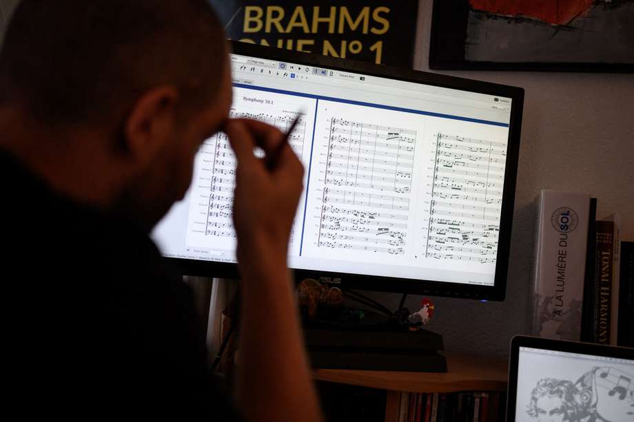 El diseñador de programas informáticos Florian Colombo (derecha) y el director Guillaume Berney miran una partitura en la pantalla de una computadora en Lausana el 2 de septiembre de 2021.