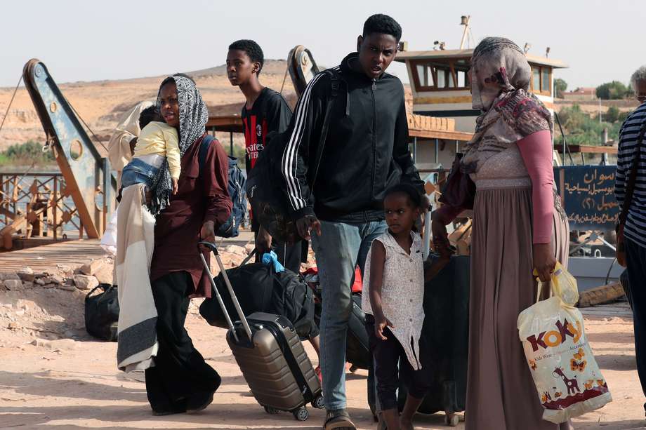Sudaneses caminan con sus pertenencias tras cruzar la frontera desde Sudán, Abu Simbel, al sur de Egipto.
