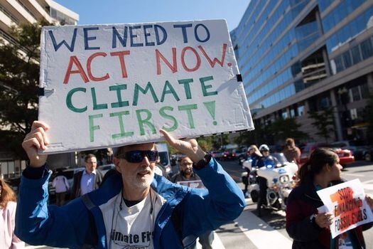 Manifestantes protestan por las inversiones del FMI y el Banco Mundial en combustibles fósiles y los instan a enfrentar el cambio climático.