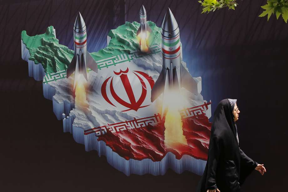 Una mujer iraní pasa junto a una pancarta antiisraelí con fotografías de misiles iraníes, en Teherán, Irán, el 16 de abril de 2024.
