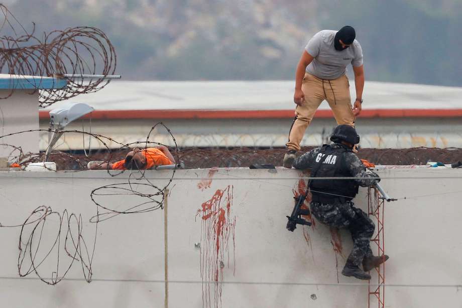 Miembros de la policía ecuatoriana son vistos junto al cuerpo de un recluso en el techo de un pabellón de la prisión Guayas 1 en Guayaquil.