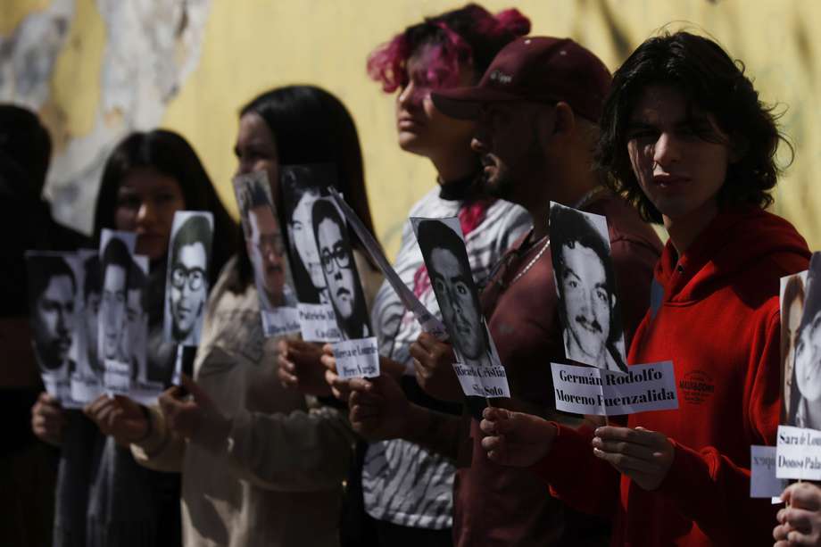 Personas sostienen pancartas, con imágenes de exestudiantes de la Universidad de Chile, víctimas de Desaparición Forzada, hoy durante la conmemoración del día internacional del Detenido Desaparecido, en Santiago (Chile). 