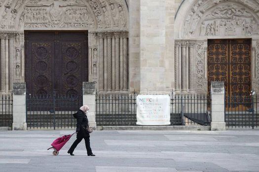 Una mujer con una máscara protectora pasa por la Basílica de Saint-Denis en Saint-Denis, cerca de París, el día diecisiete de un encierro destinado a frenar la propagación de la epidemia COVID-19. / AFP