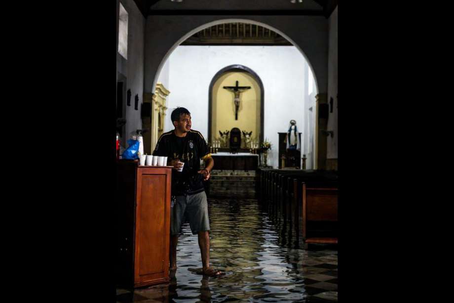 Un hombre camina en medio de la inundación en la Iglesia Tercera Orden este sábado en Cartagena (Colombia)