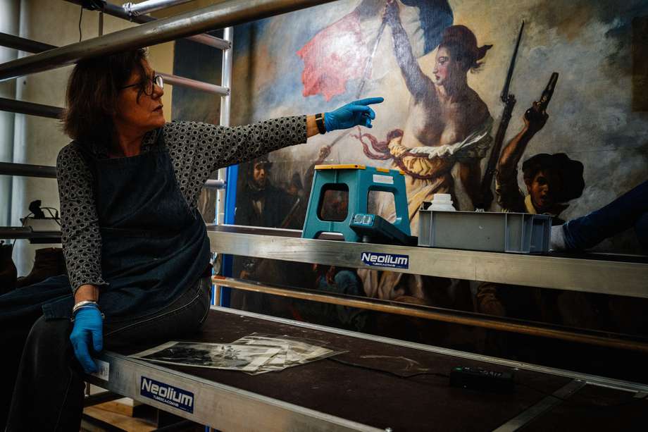 Un artista restaurador trabaja en la restauración del cuadro "La libertad guiando al pueblo" (1830) del artista francés Eugene Delacroix (1798-1863), en un laboratorio dentro del Museo del Louvre en París, el 28 de febrero de 2024.