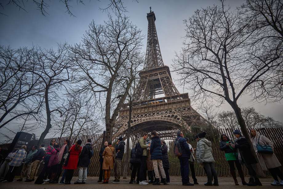 Los turistas caminan junto a la Torre Eiffel al amanecer mientras el monumento está cerrado debido a una huelga del personal por la gestión financiera del monumento por parte de la ciudad, cerrando el monumento al público durante la segunda semana de las vacaciones escolares francesas, en París el 19 de febrero de 2024. 