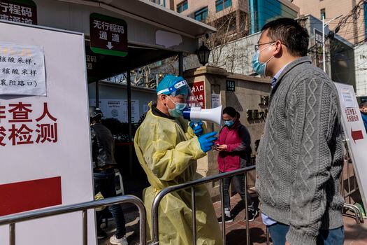 Un trabajador médico dirige a las personas que ingresan a un hospital, en Shanghái, China. 