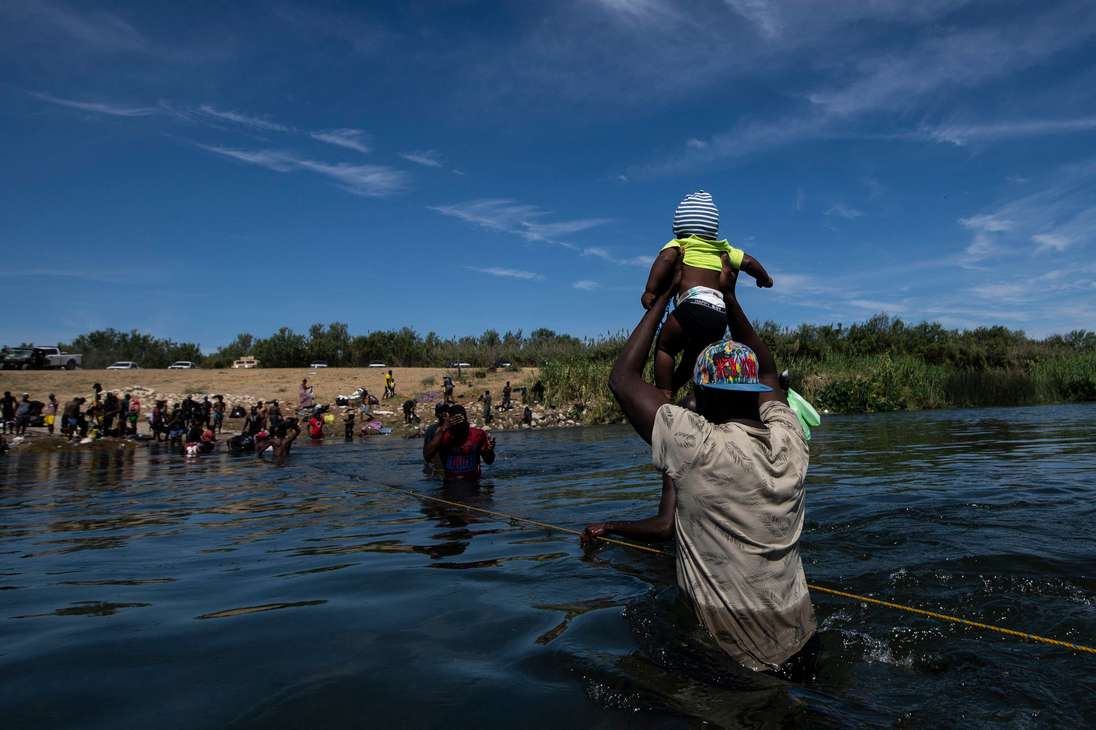 Haitian migrants cross the Rio Grande river to get food and water in Mexico, as seen from Ciudad Acuna, Coahuila state, Mexico on September 22, 2021. - Mexican President Andres Manuel Lopez Obrador urged the United States on Wednesday to act quickly to tackle the causes of the migrant crisis affecting the two neighboring countries. "Enough talking, it's time to act," Lopez Obrador told reporters as thousands of Haitian and other migrants massed on Mexico's northern border seeking access into the United States. (Photo by PEDRO PARDO / AFP)