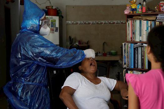 Fotografía del pasado 13 de julio que muestra a un profesional de la salud mientras le hace la prueba PCR para Covid-19 a una señora en un barrio de Cartagena. EFE/ Ricardo Maldonado Rozo