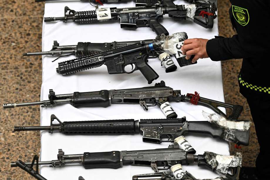 A police officer guards weapons confiscated to alleged dissidents of the Revolutionary Armed Forces of Colombia (FARC) during an operation in southwestern Colombia, as they are presented during a press conference in Bogota on January 16, 2023. The weapons and ammunition confiscated to FARC dissidents according to the Colombian National Police, is one of the largest seizures in the last years. (Photo by Raul ARBOLEDA / AFP)
