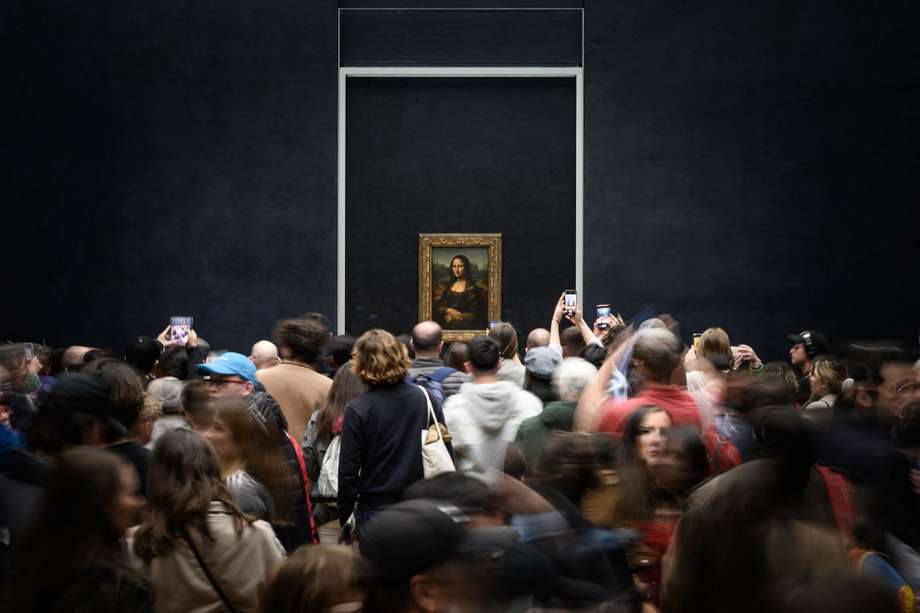 (FILES) Visitors take picture of the painting "La Joconde" The Mona Lisa by Italian artist Leonardo Da Vinci on display in a gallery at The Louvre Museum in Paris, on April 20, 2023. - President of the Louvre Laurence Des Cars announced on April 27, 2024 that she had a discussion with the Ministry of Culture to improve the exhibition conditions of the famous Mona Lisa by Leonardo da Vinci at the Louvre Museum, and possibly present it in a separate room. (Photo by LOIC VENANCE / AFP)