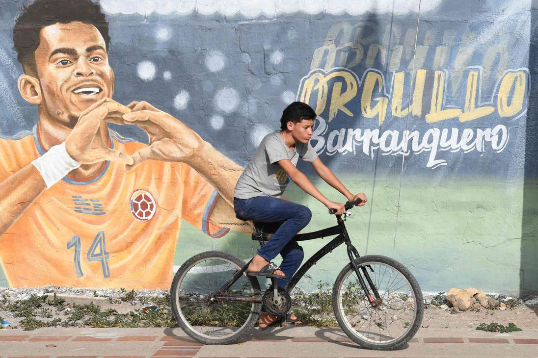 Un hombre monta en bicicleta frente a un mural que representa a la estrella del fútbol del Liverpool de Inglaterra, el colombiano Luis Díaz, en Barrancas.