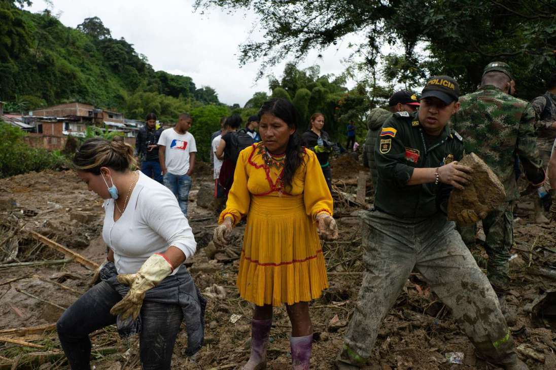 Dos mujeres y un hombre caminan entre los escombros