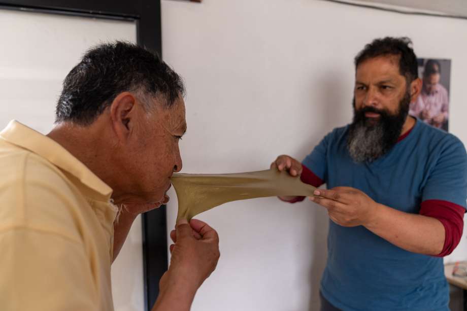 Gilberto Granja (izq.) estira una pieza de Mopa - Mopa para una de sus artesanías. Oscar, su hijo y quien heredó el oficio, le ayuda en la elaboración.