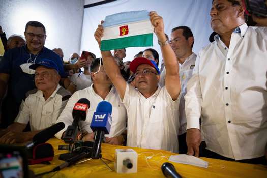 El candidato opositor a la Gobernación de Barinas, Sergio Garrido (c), muestra la bandera del estado durante una rueda de prensa desde su comando de Campaña en Barinas (Venezuela).