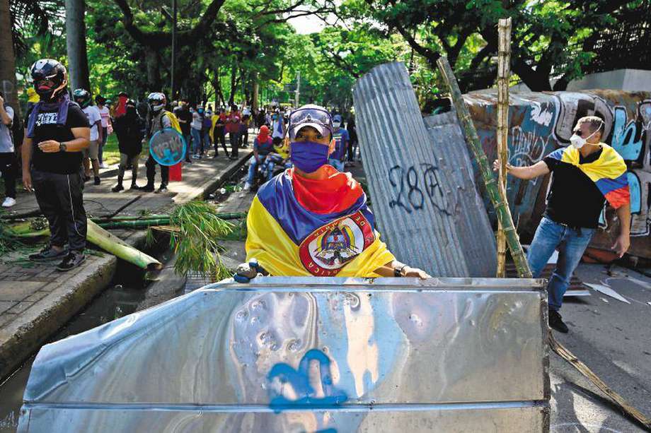 Manifestantes bloquean una calle con una barricada para protestar en contra de la reforma tributaria lanzada por el presidente Iván Duque, en Cali, Colombia, el 3 de mayo del 2021. Al menos 17 personas murieron y más de 800 resultaron heridas durante enfrentamientos que estallaron en Colombia durante cinco días de protestas en contra de la reforma fiscal propuesta por el gobierno, dijeron las autoridades el lunes. / AFP / Luis Robayo
