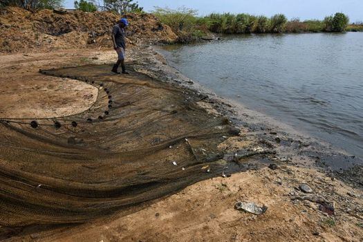 Un hombre a las orillas del Lago de Maracaibo, en donde se ha incrementado la pesca improvisada de personas que buscan qué comer. / AFP