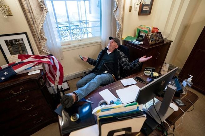 Un seguidor de Donald Trump se recuesta en la silla de la oficina de la presidenta de la Cámara, Nancy Pelosi, tras el asalto al capitolio.