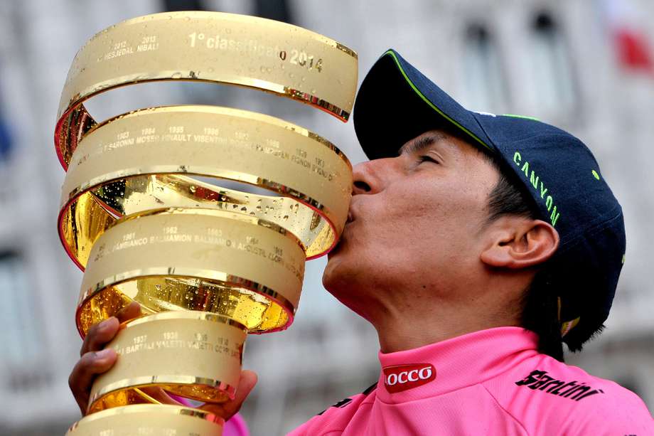 El colombiano Nairo Quintana besa el trofeo después de ganar el Giro D'Italia, carrera ciclista del Tour de Italia, en Trieste, Italia, el domingo 1 de junio de 2014. Nairo Quintana se confirmó como la próxima estrella del ciclismo al ganar el Giro d'Italia el domingo. sigue su segundo puesto en el Tour de Francia del año pasado. El especialista en escalada de 24 años del equipo Movistar ganó dos etapas y terminó con una ventaja de 3 minutos y 7 segundos sobre su compatriota colombiano Rigoberto Urán en su primera victoria en un Gran Tour. El italiano Fabio Aru finalizó tercero en la general, a 4:04 minutos. (Foto AP/Marco Alpozzi)