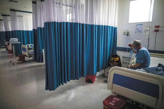 A COVID-19 patient sits on a bed at the Regional Hospital in Zipaquira, Colombia, Monday, June 28, 2021. Colombia has become a pandemic hotspot as it experiences a third wave of infections and a surge in deaths. (AP Photo/Ivan Valencia)