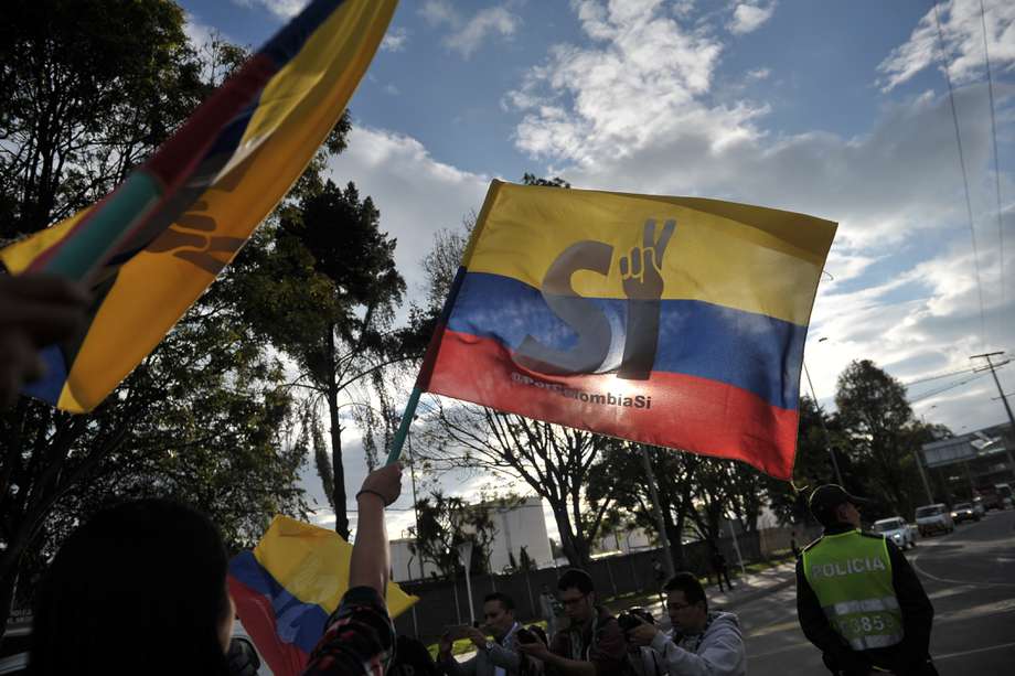 Personas con banderas esperan la llegada a Bogotá de el equipo negociador del Gobierno en el proceso de paz con las Farc.