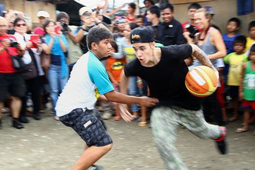 El cantante canadiense Justin Bieber juega al baloncesto rodeado de supervivientes del tifón Haiyan en la ciudad de Tacloban, en la provincia de Leyte (Filipinas)