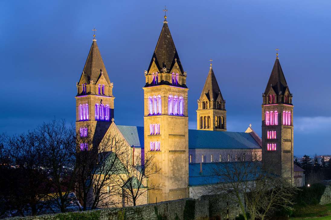 Tres de las cuatro torres de la catedral de Pecs que simbolizan las cuatro velas de una corona de Adviento se iluminan con luces violetas el tercer domingo de Adviento en Pecs, Hungría.