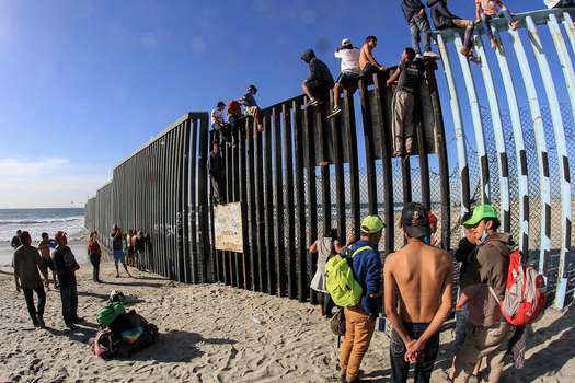 Grupo de centroamericanos en 2018 escalan el muro fronterizo en Tijuana, en el estado de Baja California (México).