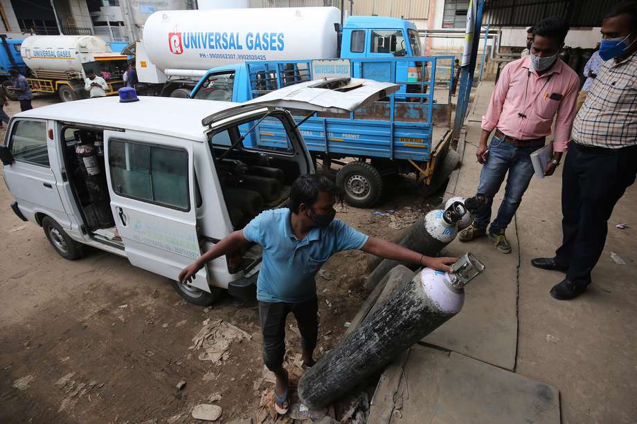 Trabajadores de un hospital de India sacan bombas de oxígeno de un vehículo.