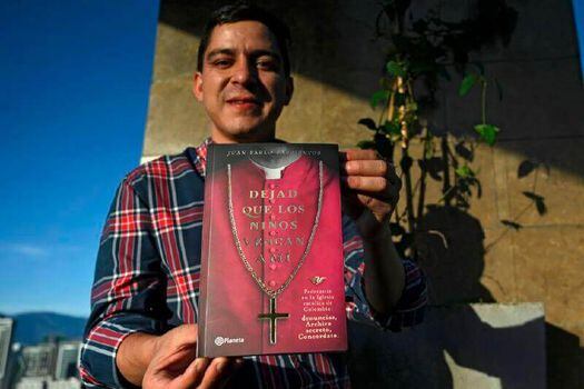 Juan Pablo Barrientos, sosteniendo una edición de "Dejad que los niños vengan a mí". 