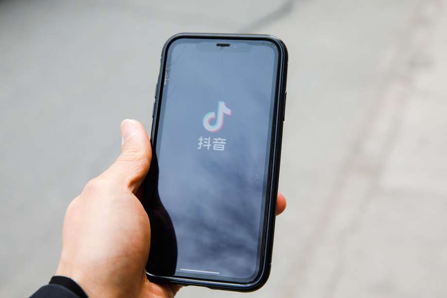 Un hombre usa la aplicación Douyin, la versión china de TikTok en su teléfono celular en la calle en Beijing, China.