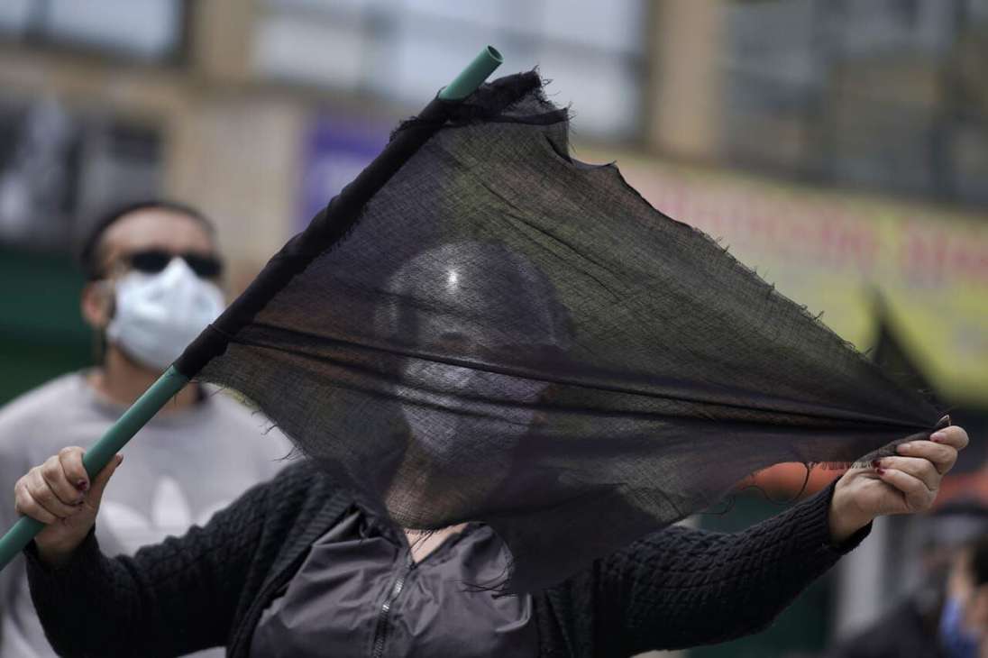 Una mujer sostiene una bandera negra.