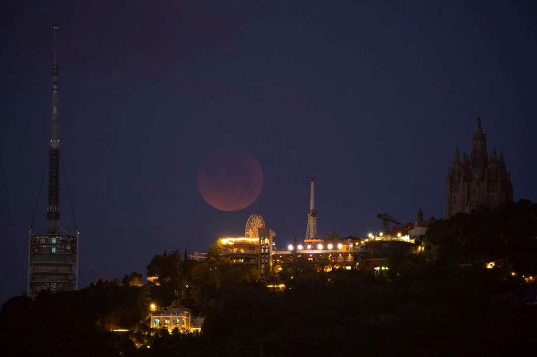 Vista del eclipse total de Luna tras el parque de atracciones del Tibidabo, en España.