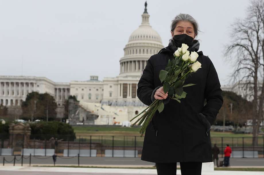 Una mujer lleva flores para colocar en el suelo cerca del edificio del Capitolio mientras rinde homenaje al oficial de policía que murió el 8 de enero de 2021 en Washington, DC. El oficial, Brian D. Sicknick, falleció después de resultar herido cuando una turba pro-Trump irrumpió y entró al Capitolio el miércoles.