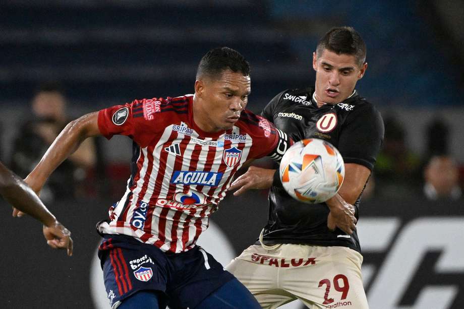 Carlos Bacca (izq.) y Aldo Corzo luchan por el balón durante el partido de fútbol de ida de la fase de grupos de la Copa Libertadores entre Junior y Universitario en Barranquilla. 