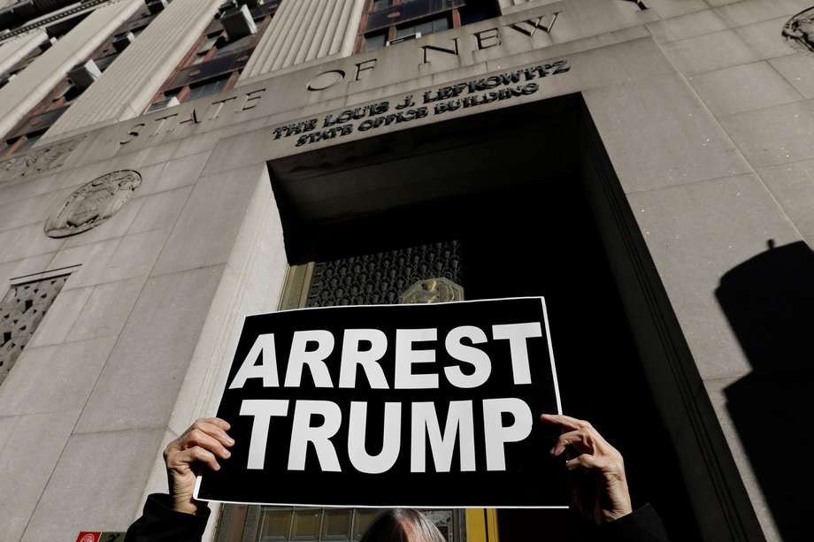 Un manifestante sostiene un cartel frente al edificio de oficinas Louis Lefkowitz del estado de Nueva York, donde se escucha el testimonio del jurado de la subvención en la posible acusación del expresidente Donald Trump, en Nueva York.
