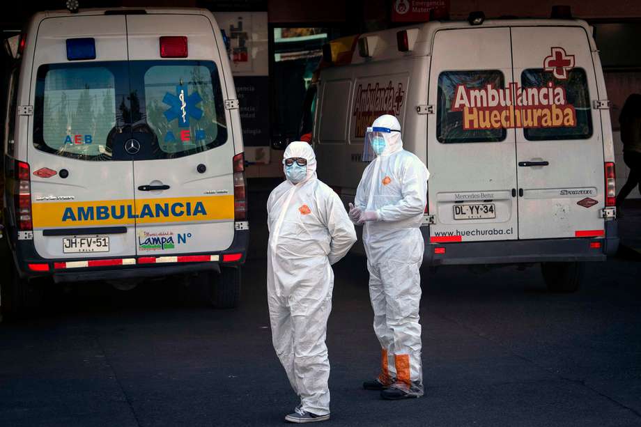 Trabajadores de la salud junto a una ambulancia que transporta a un paciente con síntomas del nuevo coronavirus mientras esperan su ingreso a un hospital en Santiago de Chile.