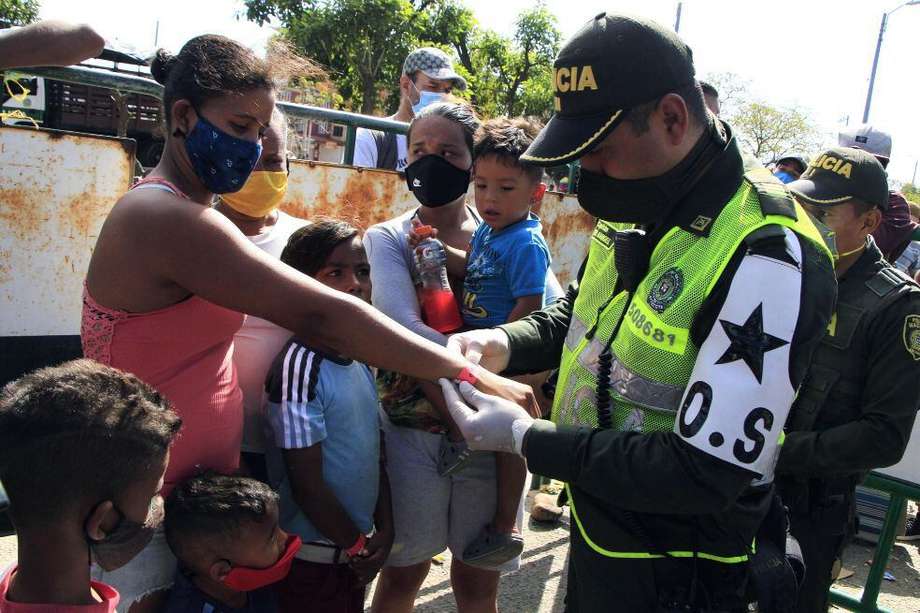 Un policía colombiano le pone un distintivo a una familia de venezolanos que quieren cruzar a su país, para trasladarlos desde el Puente Simón Bolívar hasta el Puente de Tienditas, donde permanecerán en un refugio, en Cúcuta (Colombia). / EFE